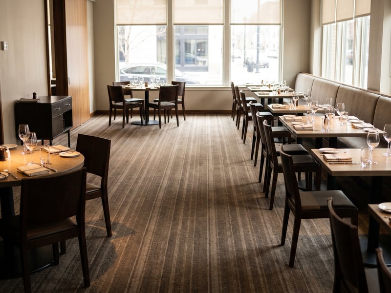 A restaurant dining room set for service on freshly cleaned commercial carpet, clean, dry, and ready before the doors open