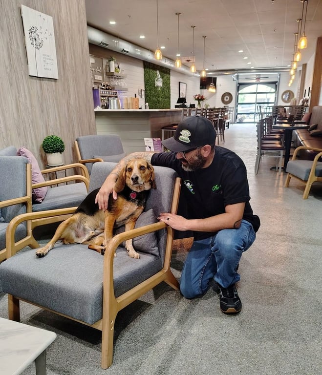 Andrew, in his Andrew's Pro Clean cap and shirt, kneeling beside a friendly rescue dog