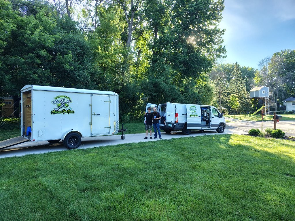 Andrew's Pro Clean's branded van and enclosed trailer in a southern Minnesota driveway, with the father-and-son team beside them