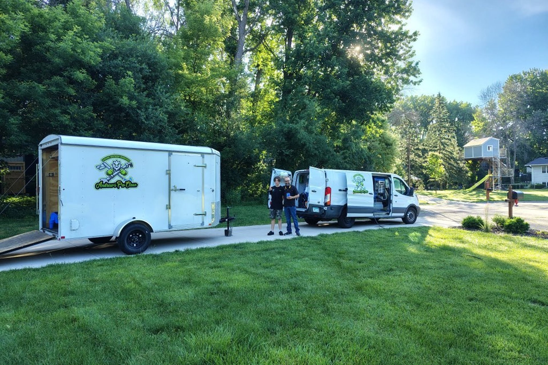 Andrew's Pro Clean's branded van and enclosed trailer in a southern Minnesota driveway, with the father-and-son team beside them