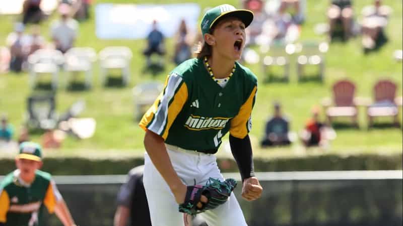 Davenport Northwest pitcher Cooper Thissen in a green and gold Midwest Region jersey shouts and pumps his fist on the mound at the Little League World Series.
