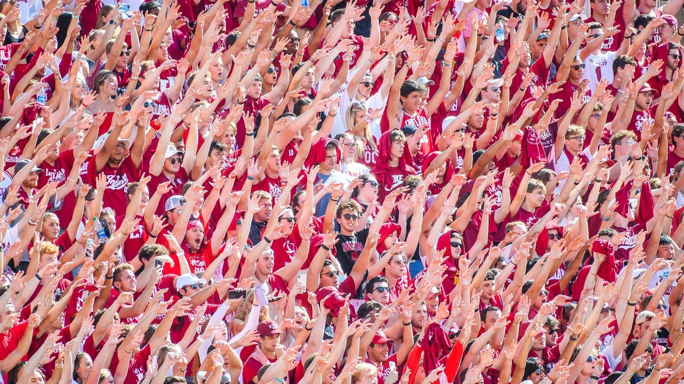 Indiana students pack the stadium bleachers in crimson with arms raised in unison during a Hoosiers home football game