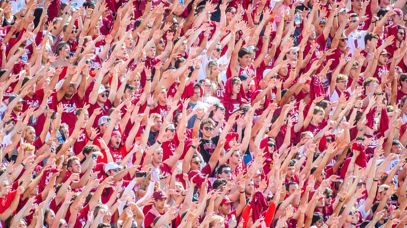 Indiana students pack the stadium bleachers in crimson with arms raised in unison during a Hoosiers home football game