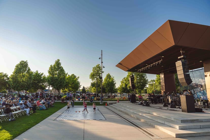 Crowds sit on the lawn in front of the downtown Elkhart amphitheater stage on a sunny evening during the Elkhart Jazz Festival.