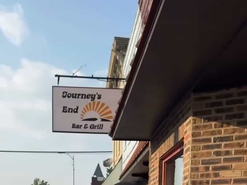 Hanging Journey's End Bar and Grill sign on the brick storefront in Bourbon