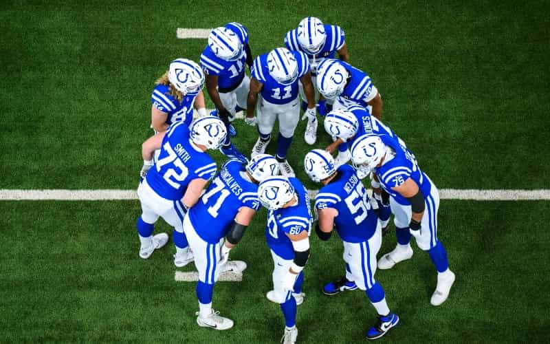 Colts players in a huddle on the field at Lucas Oil Stadium