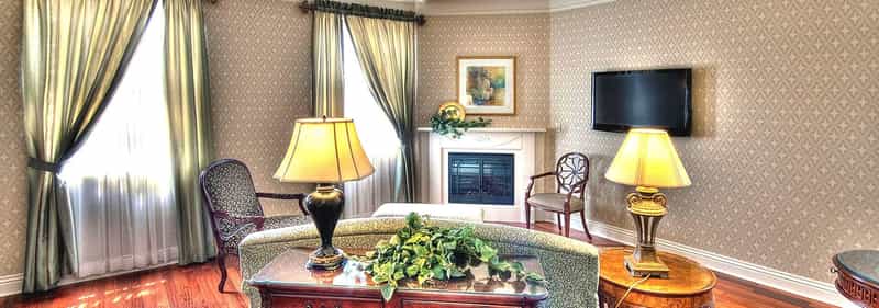 Sitting room with a fireplace, lamps and tall windows at Charley Creek Inn in Wabash