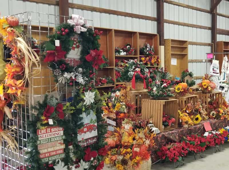 Wreaths and fall floral arrangements at a craft booth inside the fairgrounds barn at the Four Rivers Harvest Home Festival
