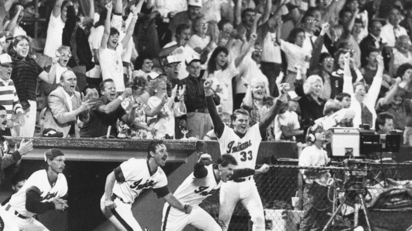 Randy Johnson, in a backwards cap, and his Indianapolis Indians teammates rush out of the dugout to celebrate the final out that clinched the 1988 Triple-A Classic over Rochester as fans cheer behind them