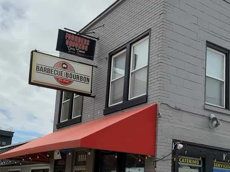 Barbecue and Bourbon hanging sign and red awning on Main Street in Speedway