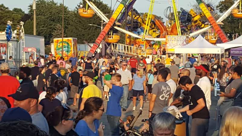 Crowded carnival midway at dusk
