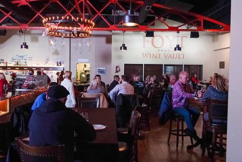 Diners at tables under a chandelier in the Foyt Wine Vault dining room in Speedway