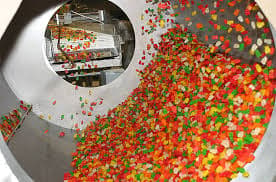 Colorful gummy candies tumbling through a drum at the Albanese candy factory