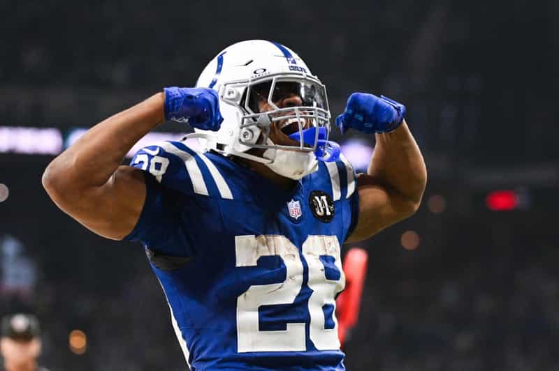 Colts running back Jonathan Taylor in his No. 28 blue jersey, flexing both arms and yelling in celebration.