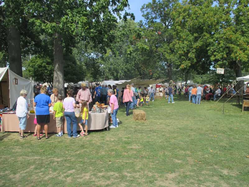 Visitors browsing pioneer craft tents under the trees at the Forks of the Wabash Pioneer Festival