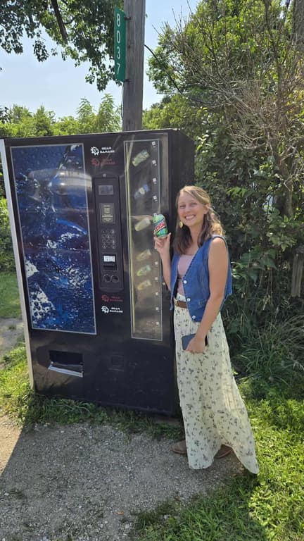 Visitor holding a can of soda next to the Packerton Pop Machine