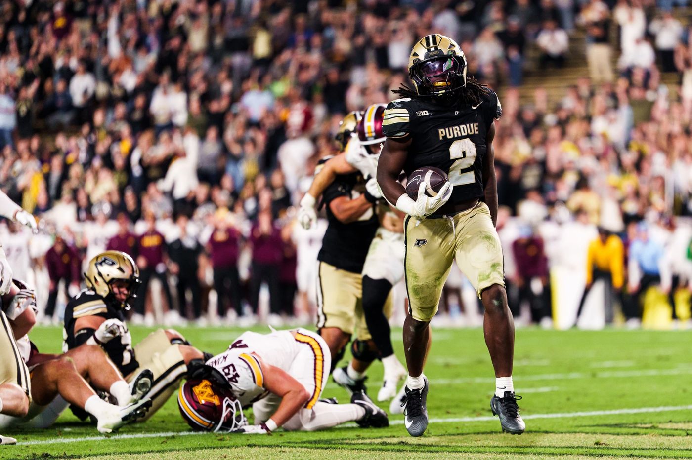 Purdue running back Fame Ijeboi, No. 2, holds the football after a touchdown run as a Minnesota defender lies on the turf at Ross-Ade Stadium
