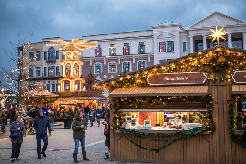 The Carmel Christkindlmarkt German Christmas market at dusk, with lit wooden vendor huts in Carmel, Indiana
