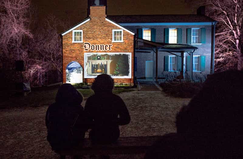 The Donner house at Conner Prairie lit up at night during A Merry Prairie Holiday