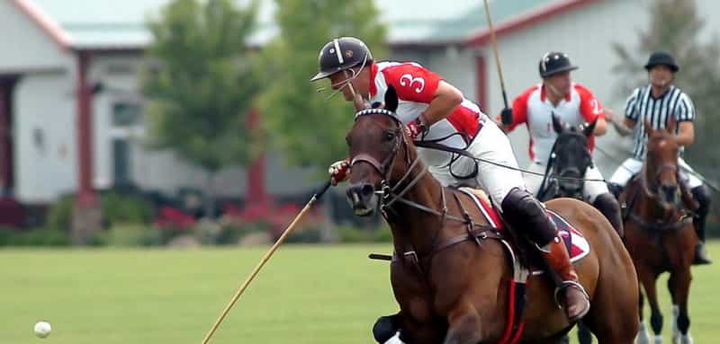 Polo players on horseback chase the ball mid-match at Hickory Hall Polo Club in Whitestown, Indiana