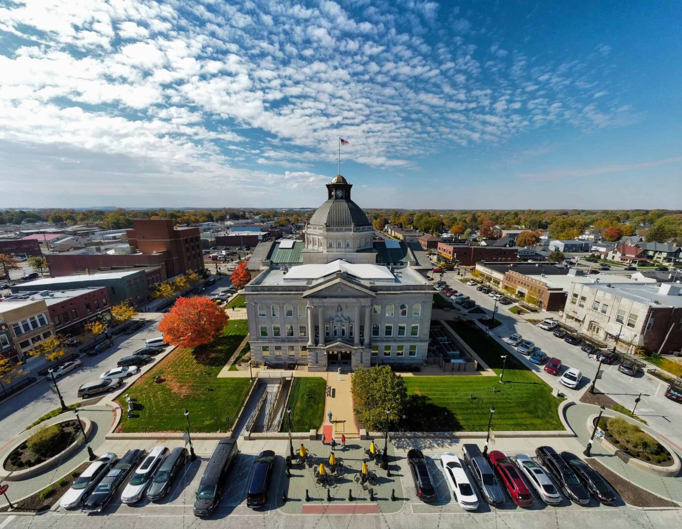 Aerial view of the Boone County courthouse and downtown square in Lebanon, Indiana, with fall foliage and parked cars lining the street