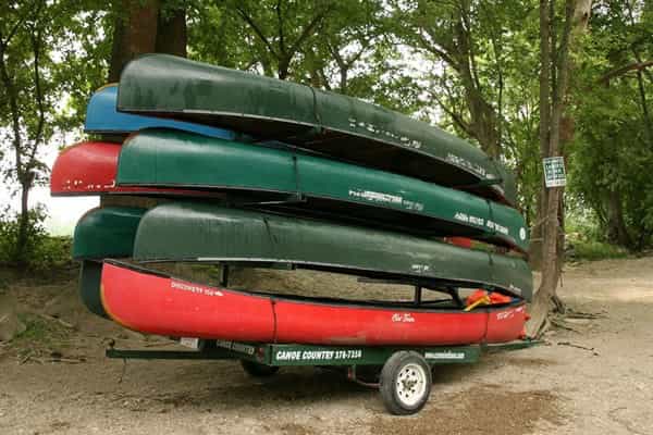 Green and red canoes stacked on a Canoe Country trailer near Daleville