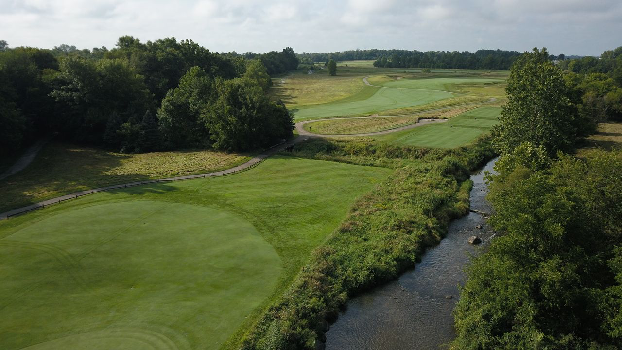 Aerial view of golf course greens and fairways along a rocky creek lined with trees near Lebanon, Indiana