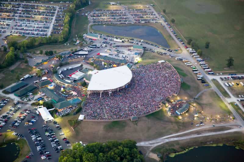 Aerial view of a packed Ruoff Music Center amphitheater in Noblesville at dusk, ringed by full parking lots during a summer concert.