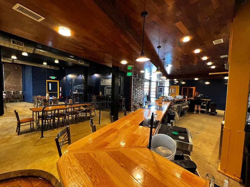 Long wooden bar and dining tables inside The Hangar, with a Hangar sign and a Lucas Oil Stadium blueprint on the navy walls