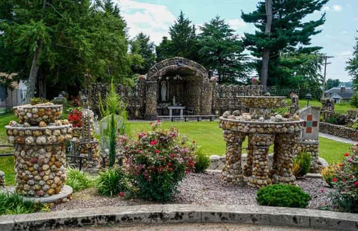 Geode-covered columns, an arched stone shrine and rose beds on the lawn of the Geode Grotto at Providence Home in Jasper, Indiana