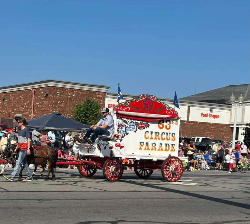 A decorative horse-drawn ‘63rd Circus Parade’ wagon rolls past spectators at the Peru Circus City Festival