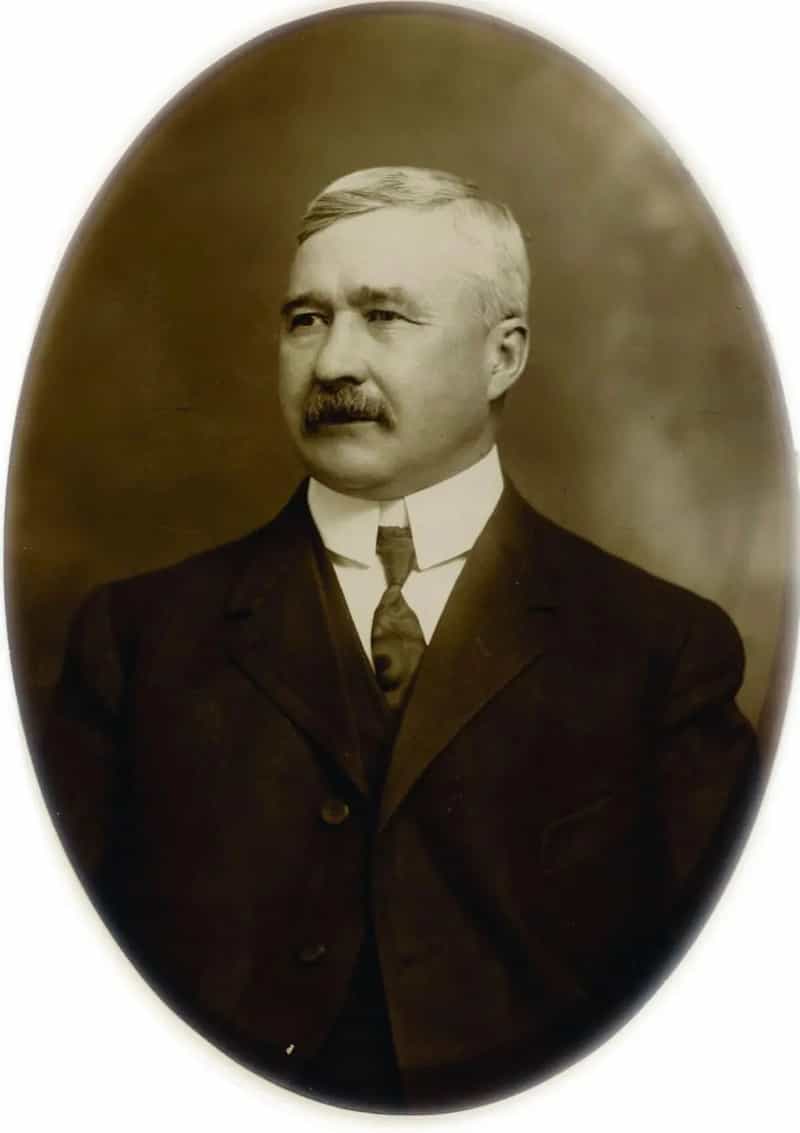 Oval sepia portrait of Kokomo inventor Elwood Haynes with gray hair and mustache, wearing a dark suit and tie