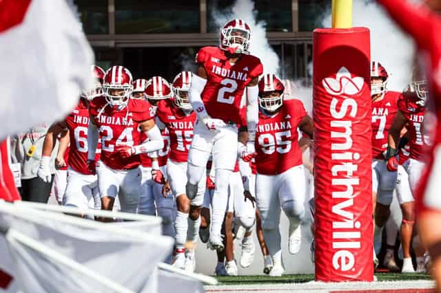 The Indiana Hoosiers football team runs onto the field through smoke past the goal-line pylon before a home game