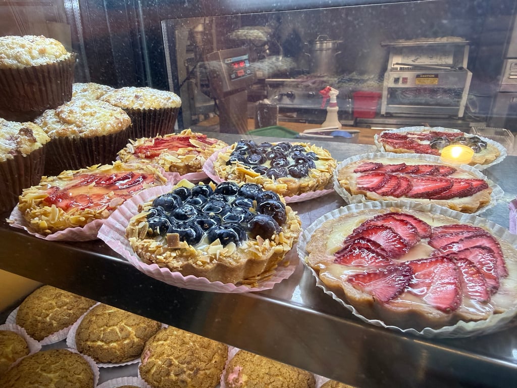 Fresh strawberry, blueberry and almond fruit tarts and crumb muffins in the display case at René's Bakery.