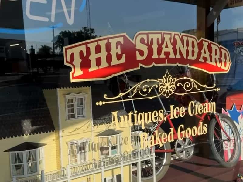 Front window of The Standard with its gold lettering for antiques, ice cream and baked goods in Bourbon
