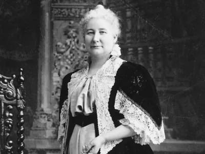 Black-and-white portrait of May Wright Sewall, a woman with pinned white hair wearing a dark jacket with a lace collar and cuffs