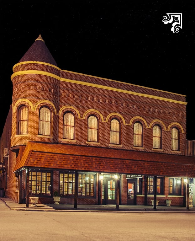 The Old Colonial Inn lit up at night inside the former 1894 Hotel Kentland building, a brick corner building with a turret on the courthouse square in Kentland, Indiana
