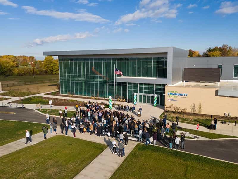 Aerial view of a crowd gathered outside the glass entrance of the Fishers Community Center on a sunny fall day