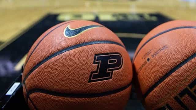 Two Nike basketballs stamped with the Purdue Boilermakers P logo sitting courtside on a gold and black hardwood floor