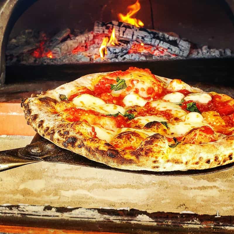 Wood-fired pizza on a peel in front of the oven at Battista's Artisan Pizzeria in Crown Point