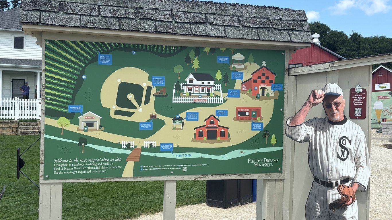 An illustrated site map of the Field of Dreams Movie Site next to a life-size cutout of a 1919 Chicago White Sox ghost player.