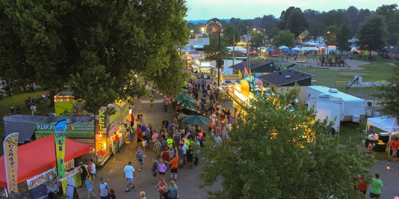 Evening aerial view of the Swiss Wine Festival midway and food booths in a riverside park in Vevay, Indiana