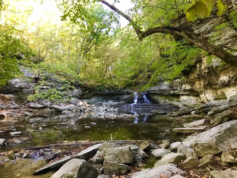 Waterfall spilling into a rocky limestone canyon under green trees at McCormick's Creek State Park