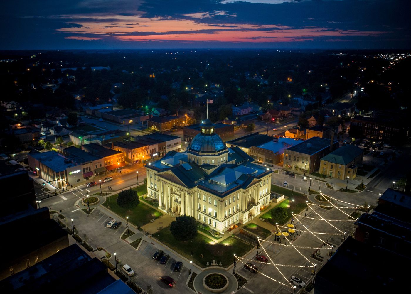 Aerial view of the lit Boone County Courthouse and string-lit square in downtown Lebanon, Indiana at dusk