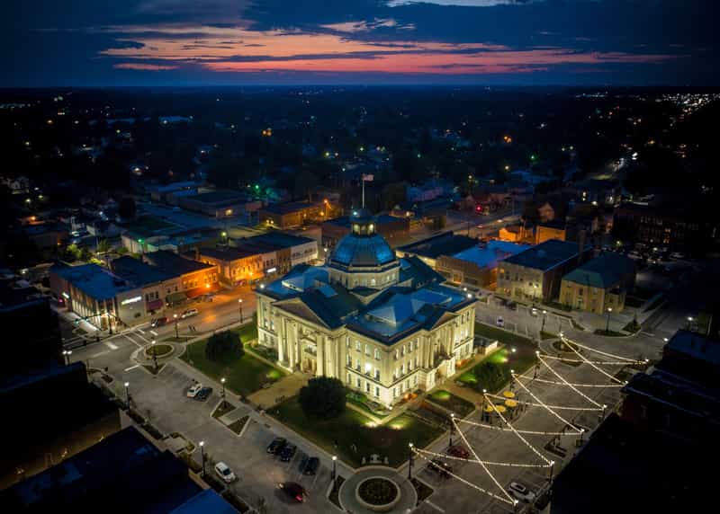 Aerial view of the lit Boone County Courthouse and string-lit square in downtown Lebanon, Indiana at dusk