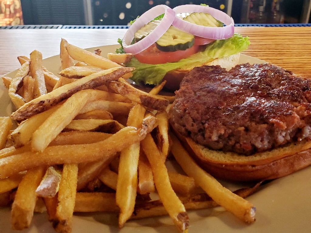 A burger topped with lettuce, tomato, red onion and pickles served with a plate of hand-cut fries at a downtown Seymour, Indiana restaurant