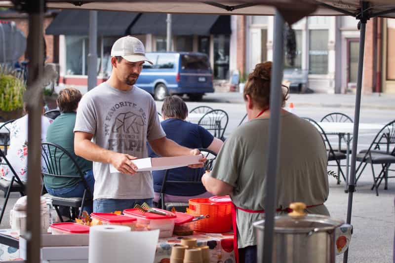 Volunteers serving chili under a tent on Main Street at the Farmland chili cook-off