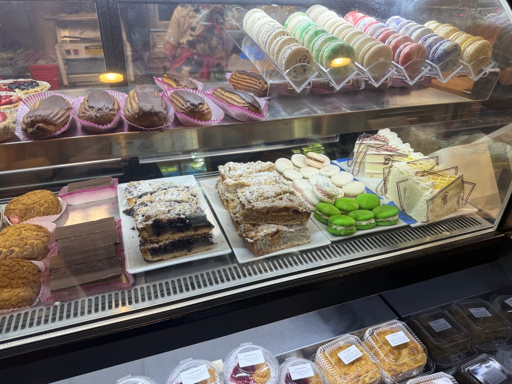 The glass pastry case at René's Bakery filled with rows of colorful French macarons, chocolate éclairs, fruit tarts and powdered-sugar cake bars.