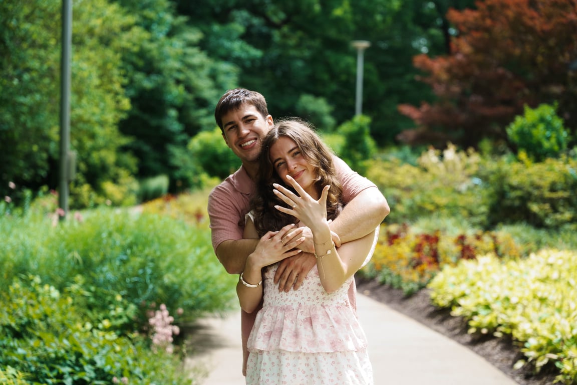 Get Indiana video editor Robert Porter and his fiancée after their engagement at Newfields, embracing on a sunlit garden path with the new ring held up to the camera