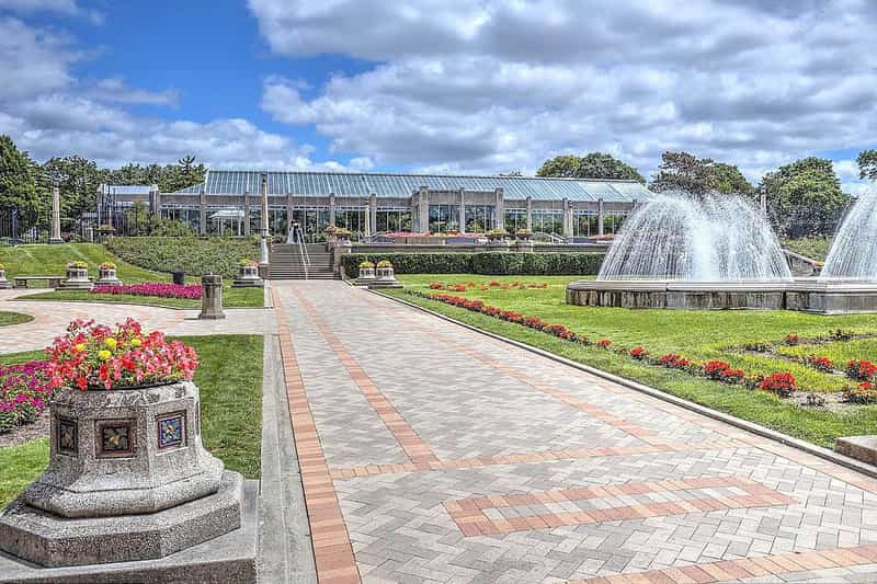 The Sunken Garden fountains and brick walkway with the Garfield Park Conservatory glass house behind, Indianapolis, Indiana
